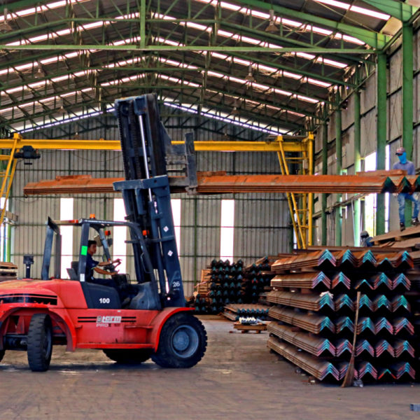 A man driving a forklift that is stacking pressed steel sheets